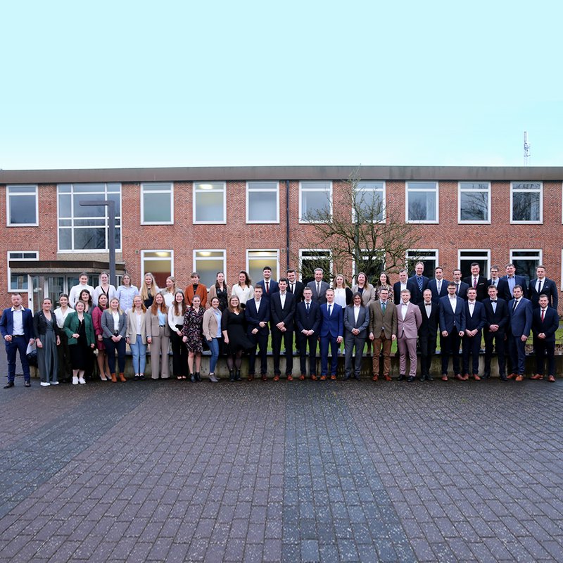 die Absolventinnen und Absolventen des Wintersemesters mit Dekan Prof. Martin Braatz stehen vor dem Gebäude auf dem Campus in Osterrönfeld