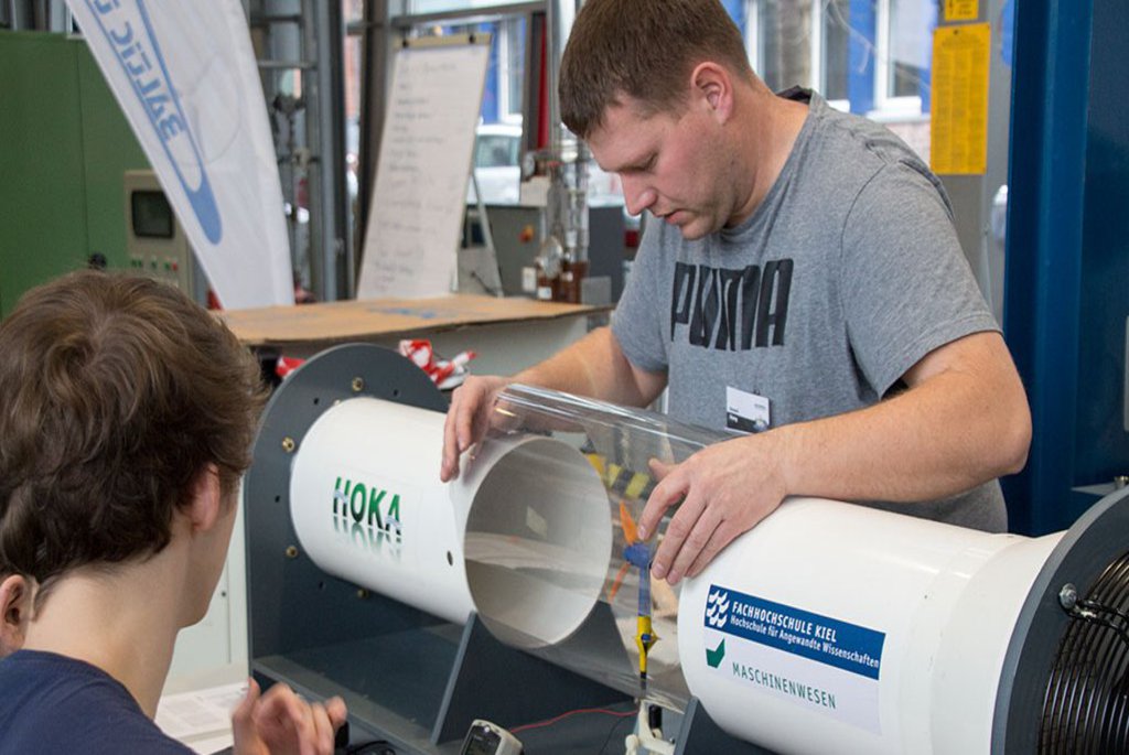 Zwei Männer stehen vor einer Aparatur in einem Gebäude des FB Maschinenwesen.