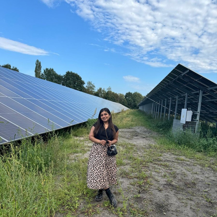 eine Frau steht vor einer Grünfläche mit Solarpanels