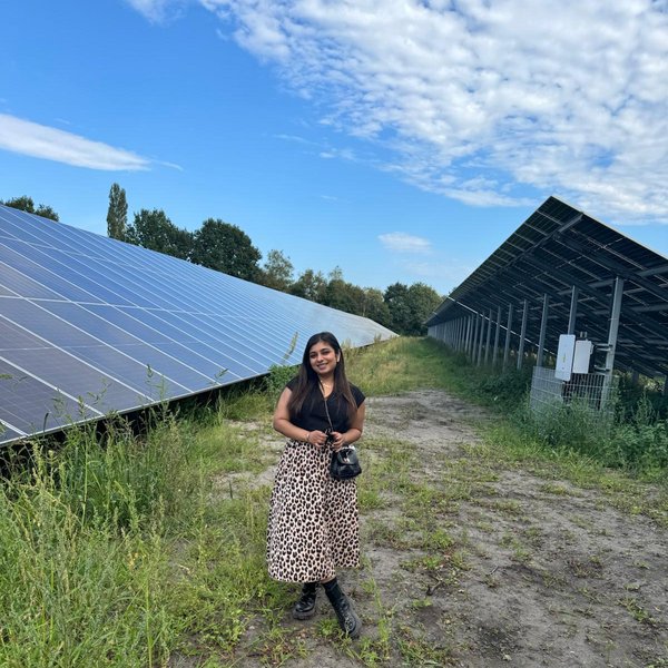 eine Frau steht vor einer Grünfläche mit Solarpanels