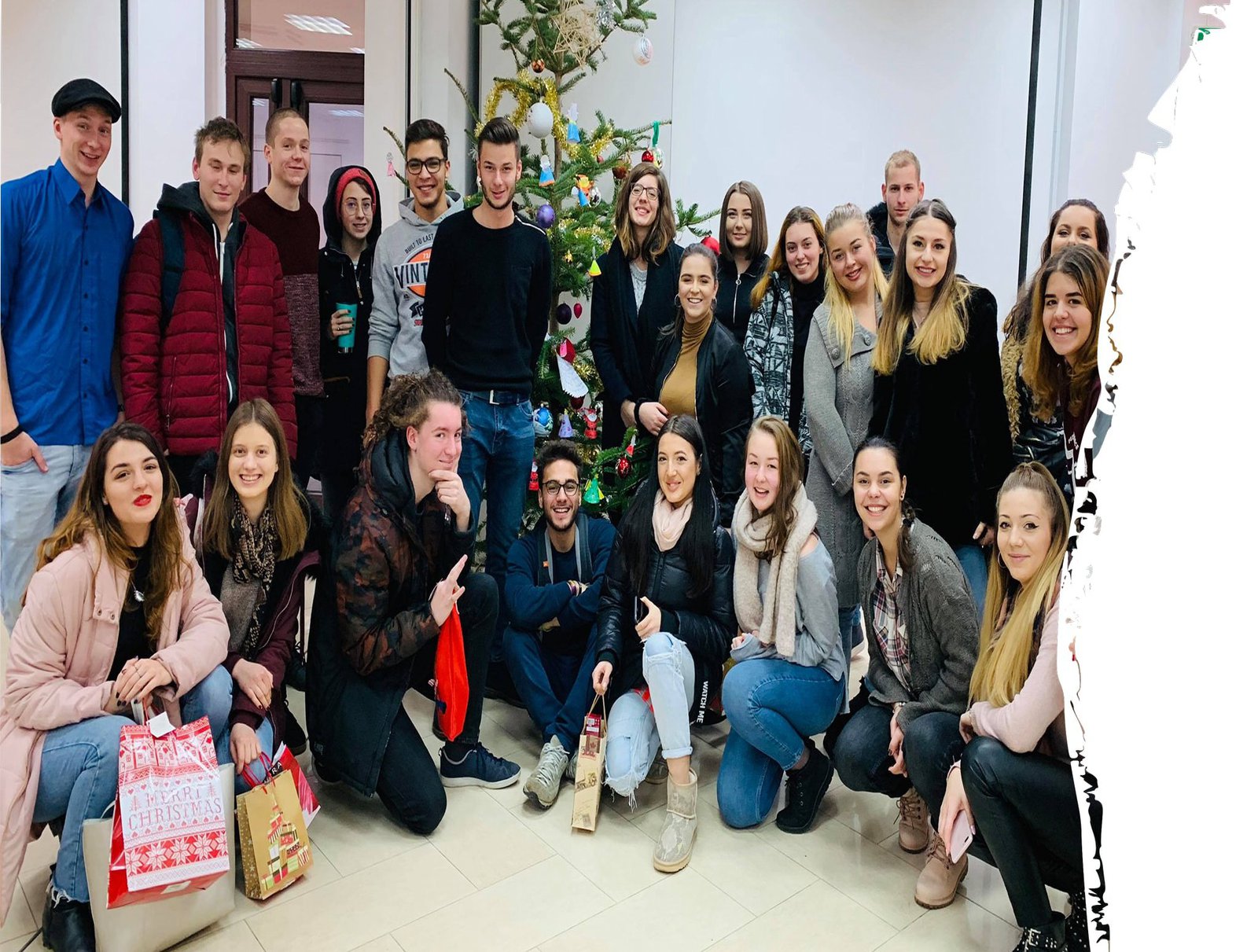 Eine Gruppe studierender posiert vor einem geschmückten Tannenbaum.