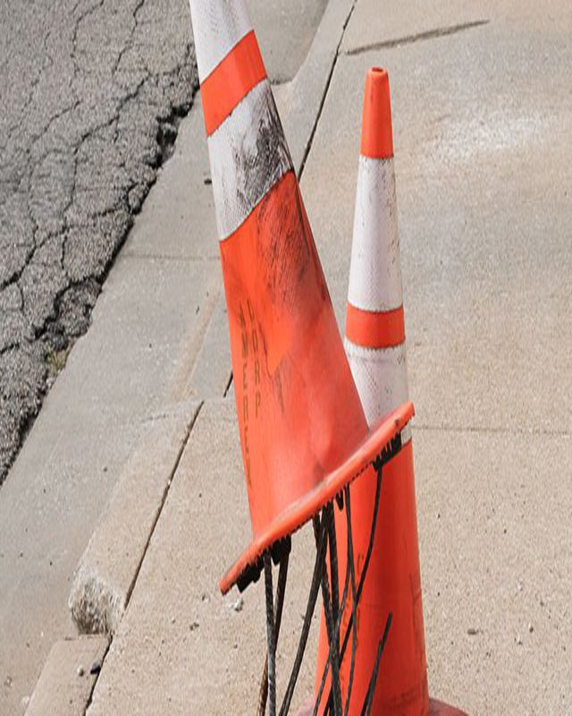 Zwei Warnkegel, einer der beiden hängt auf aus dem Boden ragenden Metallstäben.