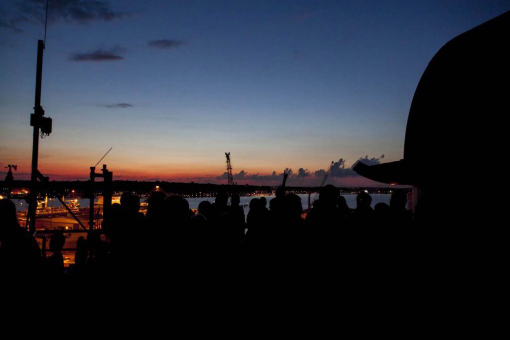 Die Silhouette einer Menschenmenge umgeben von dem dumpfen Licht des Sonnenuntergangs.