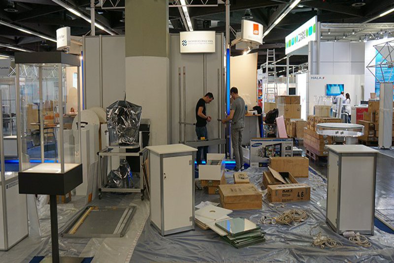 Zwei Männer sind dabei einen mittelgroßen Messestand aufzubauen.