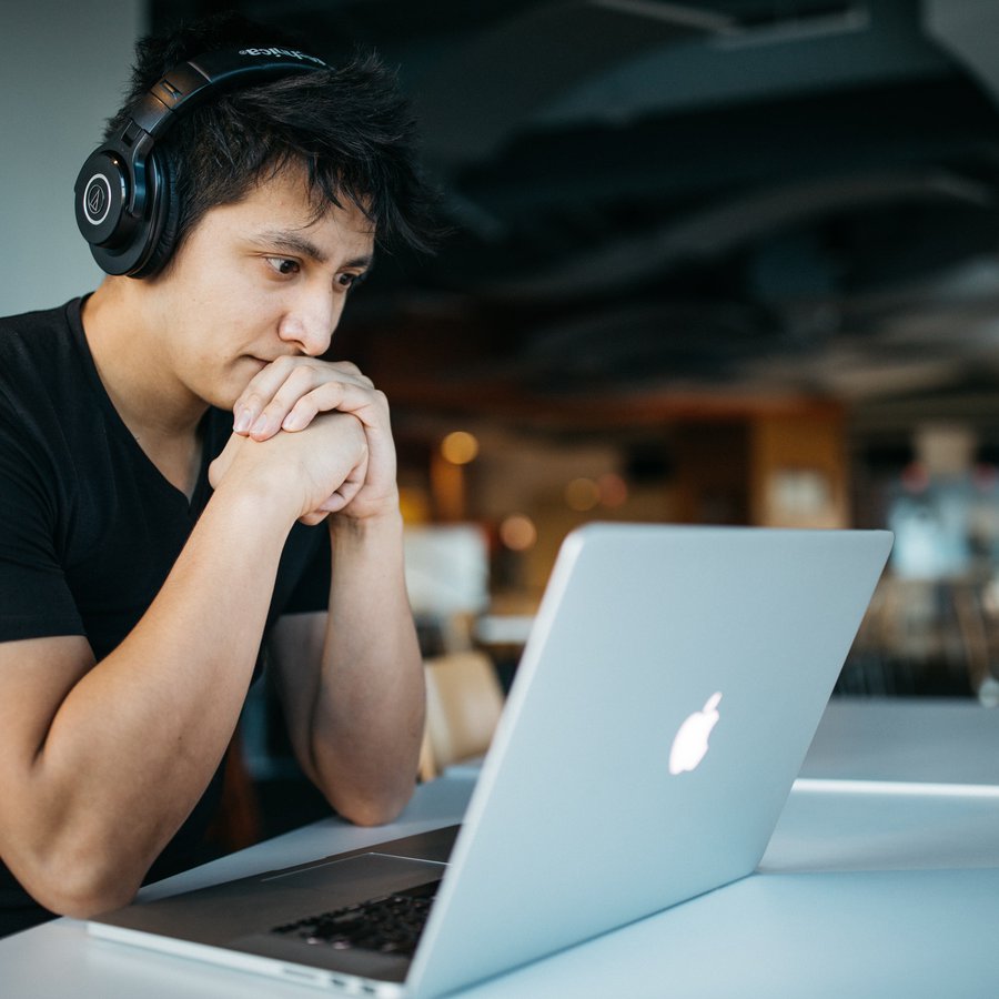 Foto: Hicks Ein Mann sitzt vor seinem Laptop, in grüblerischer Pose.