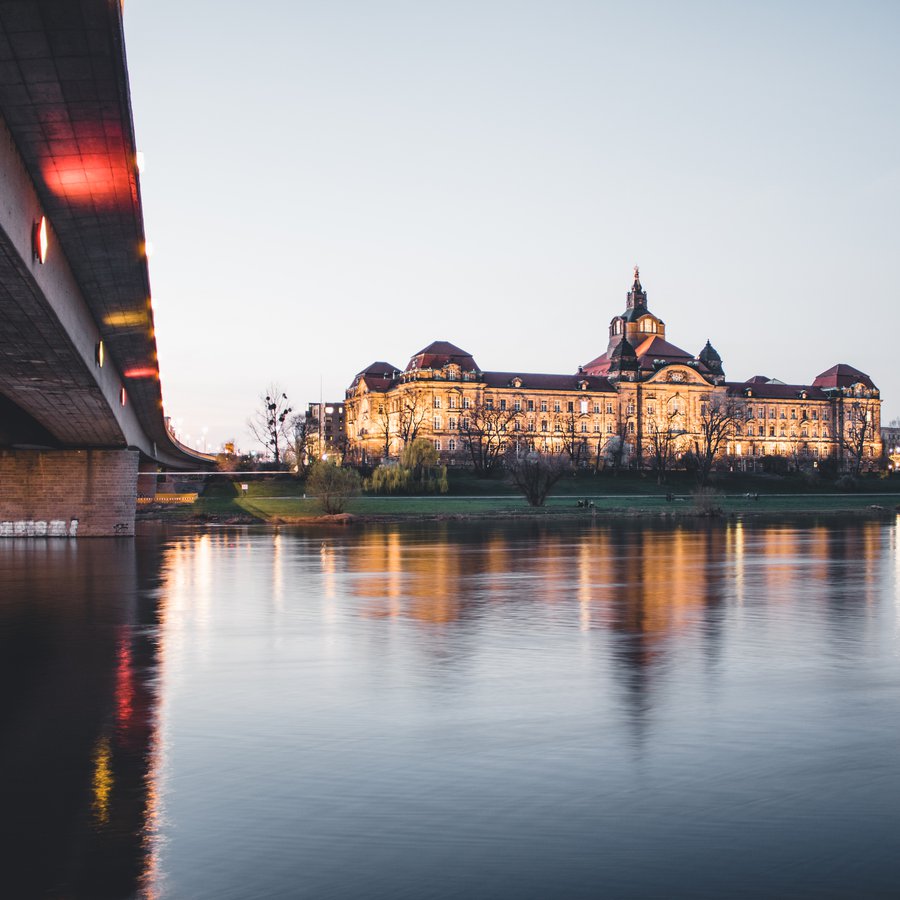 Die Sächsische Staatskanzlei Auf der linken Bildseite ersteckt sich die Unterseite einer Betonbrücke, am gegenüberliegenden Ufer des Flusses, in diesem Fall der Elbe, ist die Sächsische Staatskanzlei zu sehen.