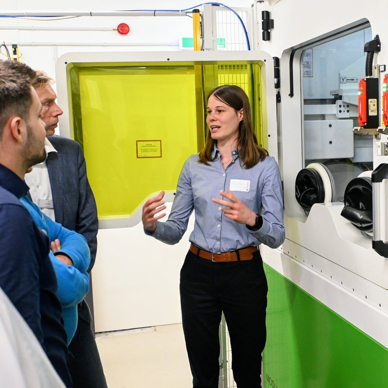 Sira Görns erläutert Besuchern der Spätschicht die Funktionsweise der Laser-Metallpulver-Auftragsanlage.