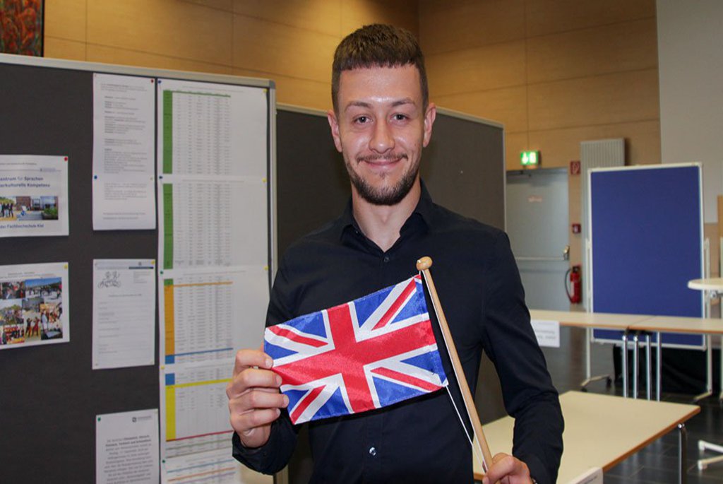 Ein Mann posiert mit einem Wimpel der englischen Flagge in den Händen.