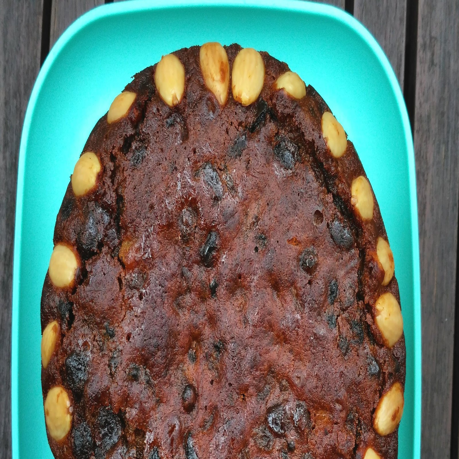 Ein braungebackener KUchen liegt auf einem türkisenen Tablet.