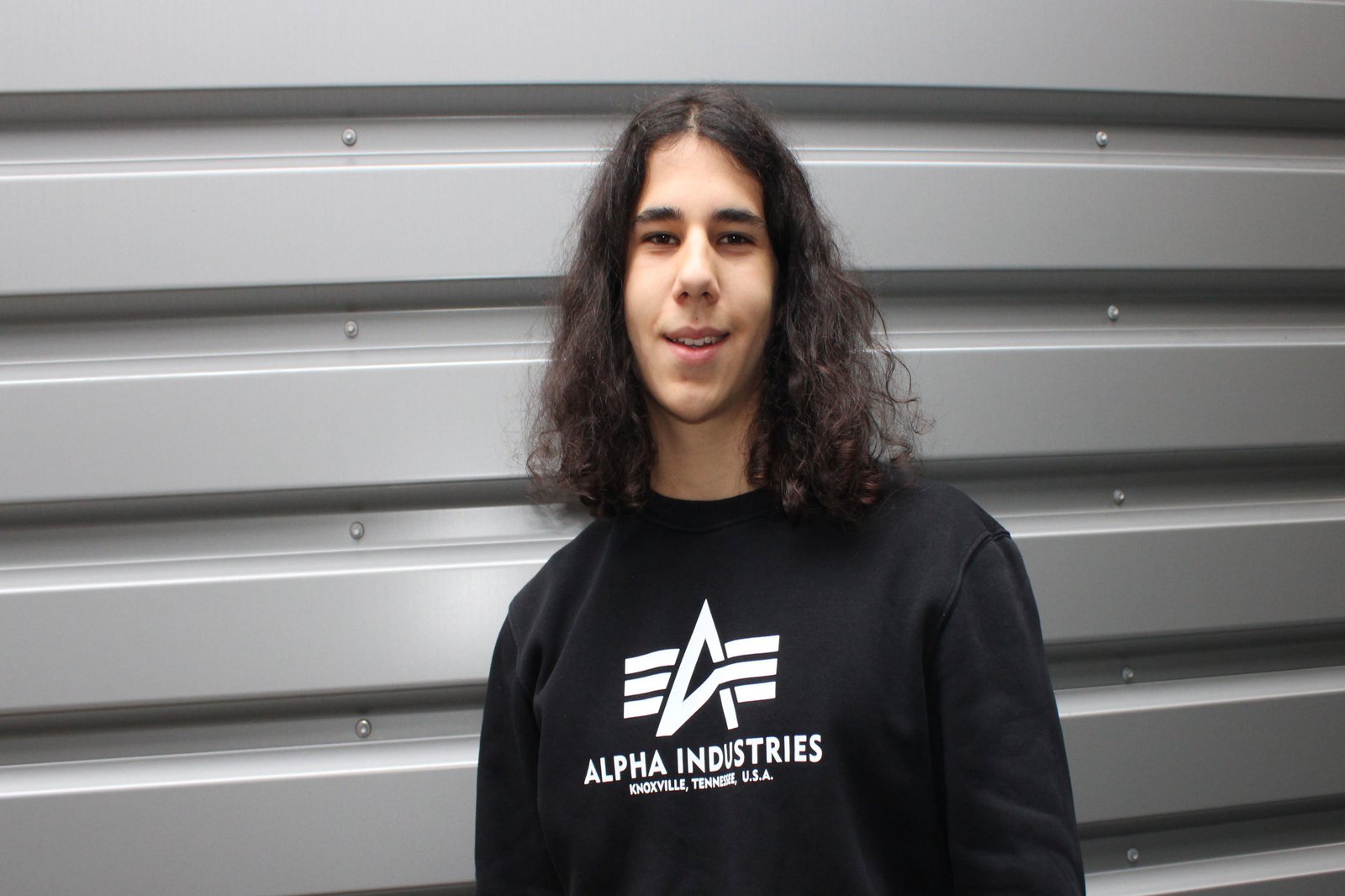 Ein Mann posiert vor einer grauen Wand.