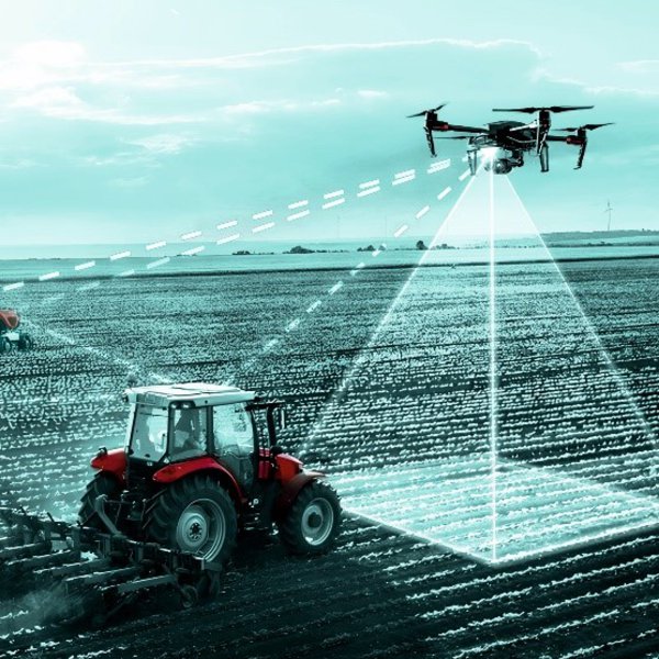 Auf der Grafik sind ein Trecker, Mähroboter und Drohnen zu sehen, es soll ein kollaboratives Netzwerk aus Mensch/Maschine und KI zur nachhaltigen Optimierung der Arbeitsprozesse und Flächenproduktivität darstellen