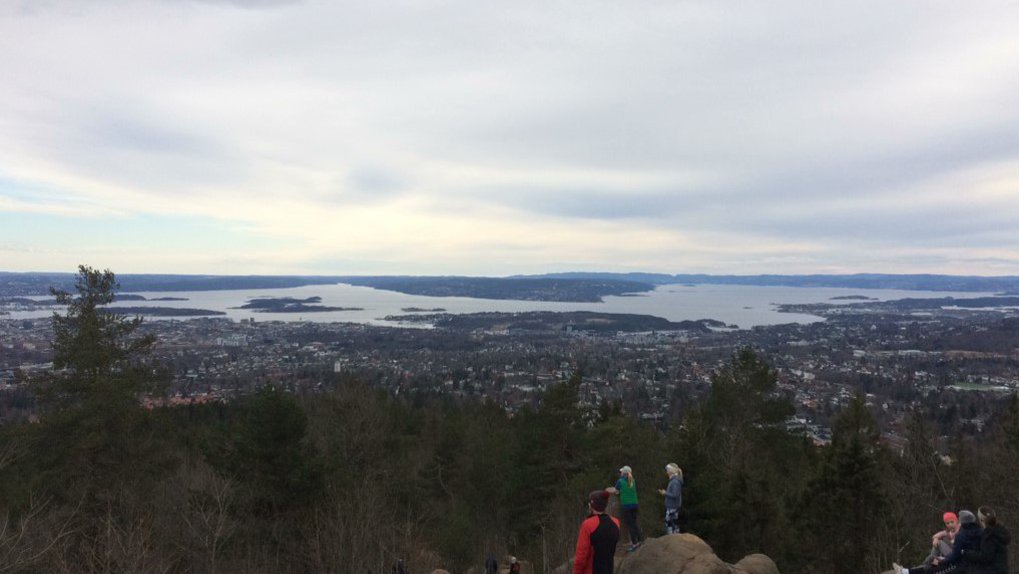 Das Bild zeigt eine Stadt und ein dahinterliegendes Gewässer, aufgenommen von der Spitze eines Berges.