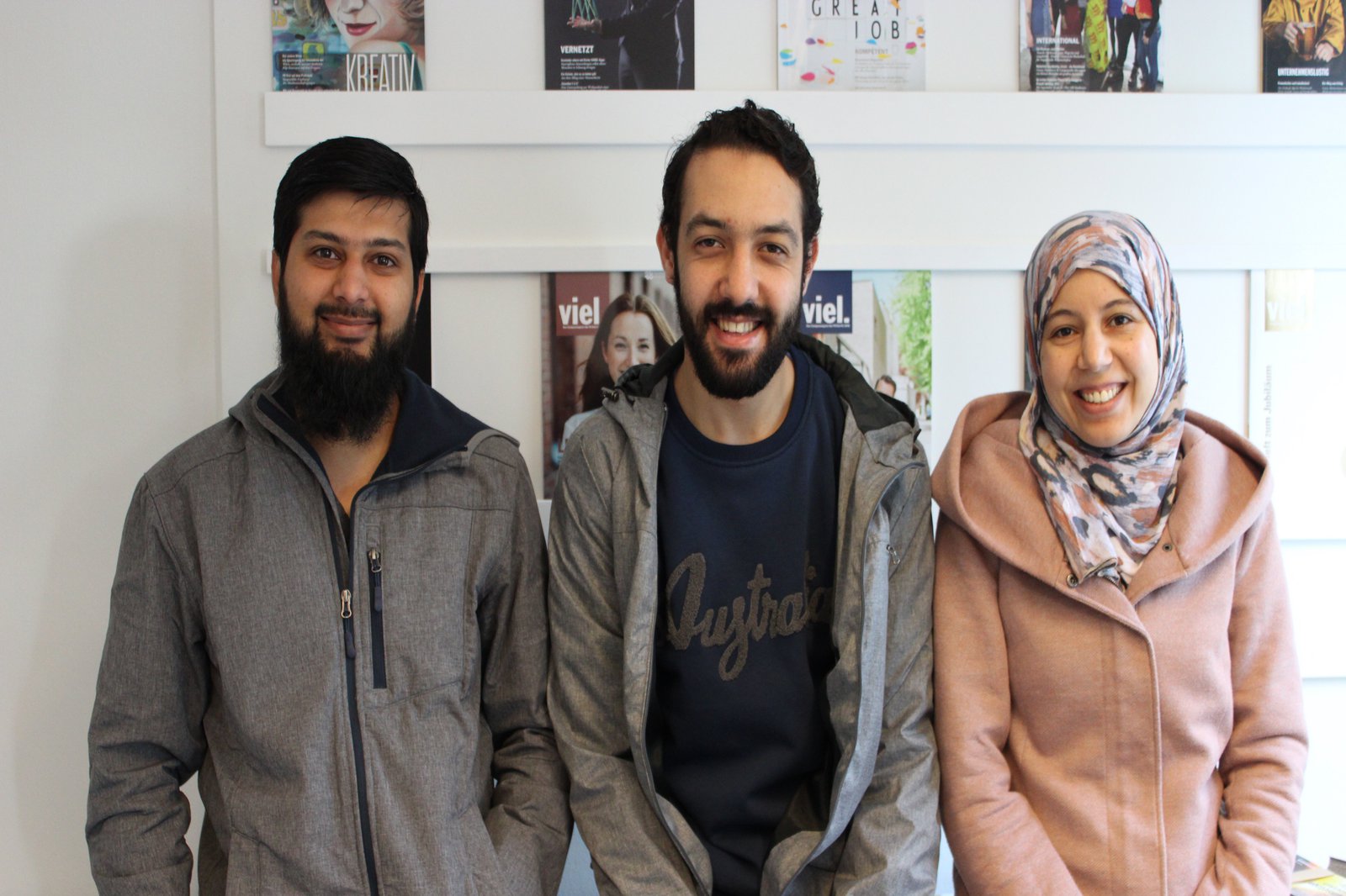 Eine Frau und zwei Männer posieren im Konferenzraum der Stabstelle Strategische Kommunikation.