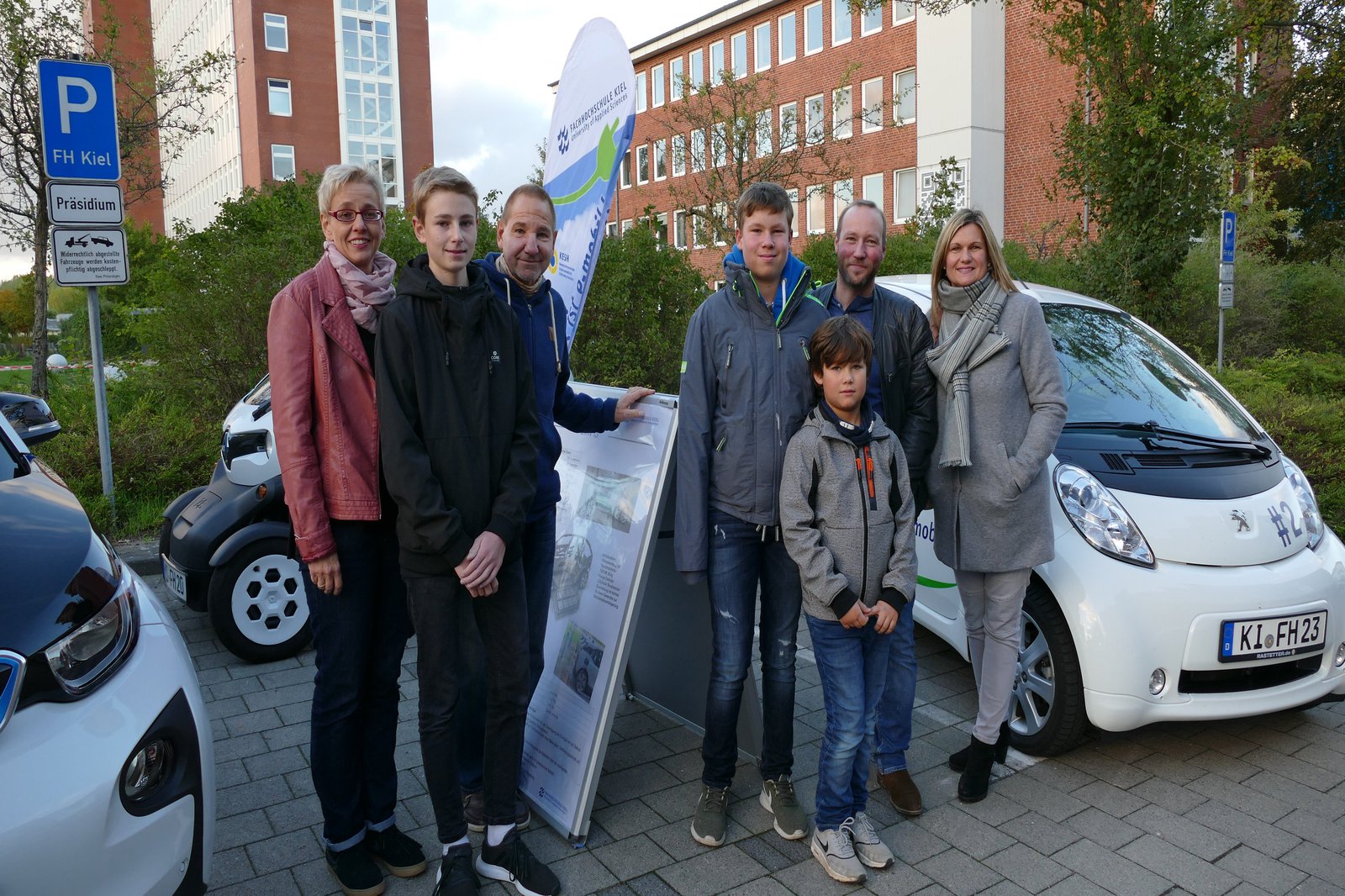Zwei Familien stehen auf einem Parkplatz nebeneinander.