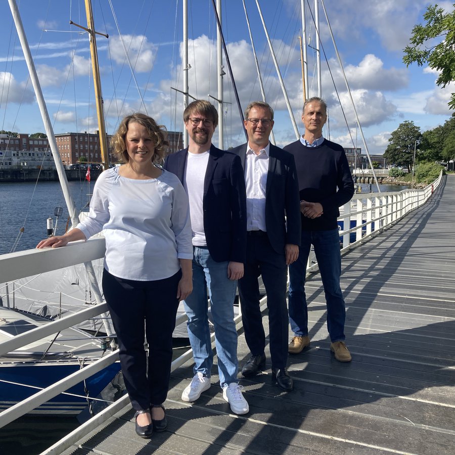 Einew Frau und drei Männer stehen auf einem langen Steg, auf der linken Seite liegen Segelboote. Vorne steht Pro. Stefanie Mentrup, dahinter Prof. Michael Müller, dahinter Prof. Thilo Rohlfs und dahinter Prof. Joachim Laudien.