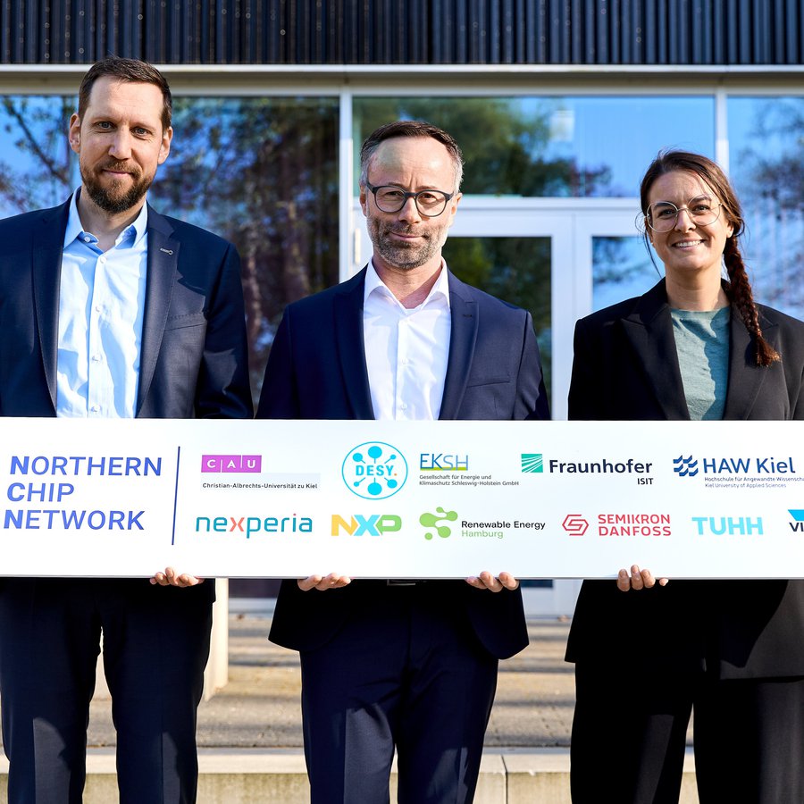 zwei Männer und eine Frau halten ein Schild mit verschiedenen Logos in Händen