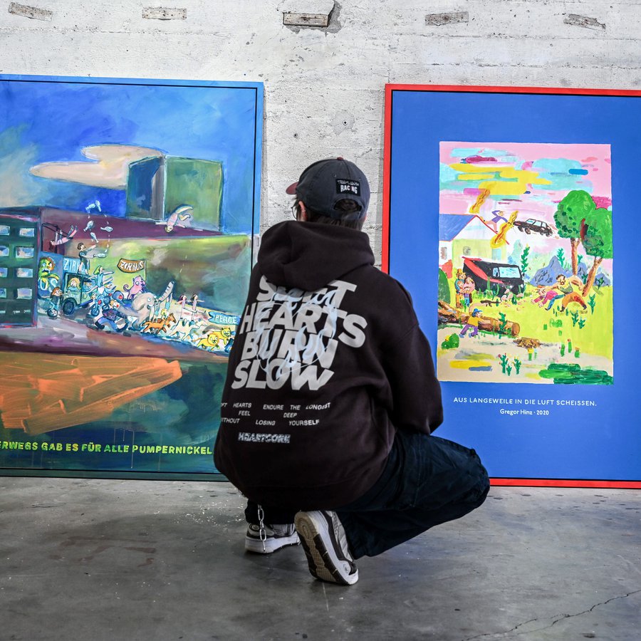 Bunker-D - Gregor Hinz - Akt, Action und Stillleben Eine junger Person hockt azf de Bodne und betrachtet zwei an der Wand lehnende Bilder von Gegor Hinz im Bunker-D der FH Kiel