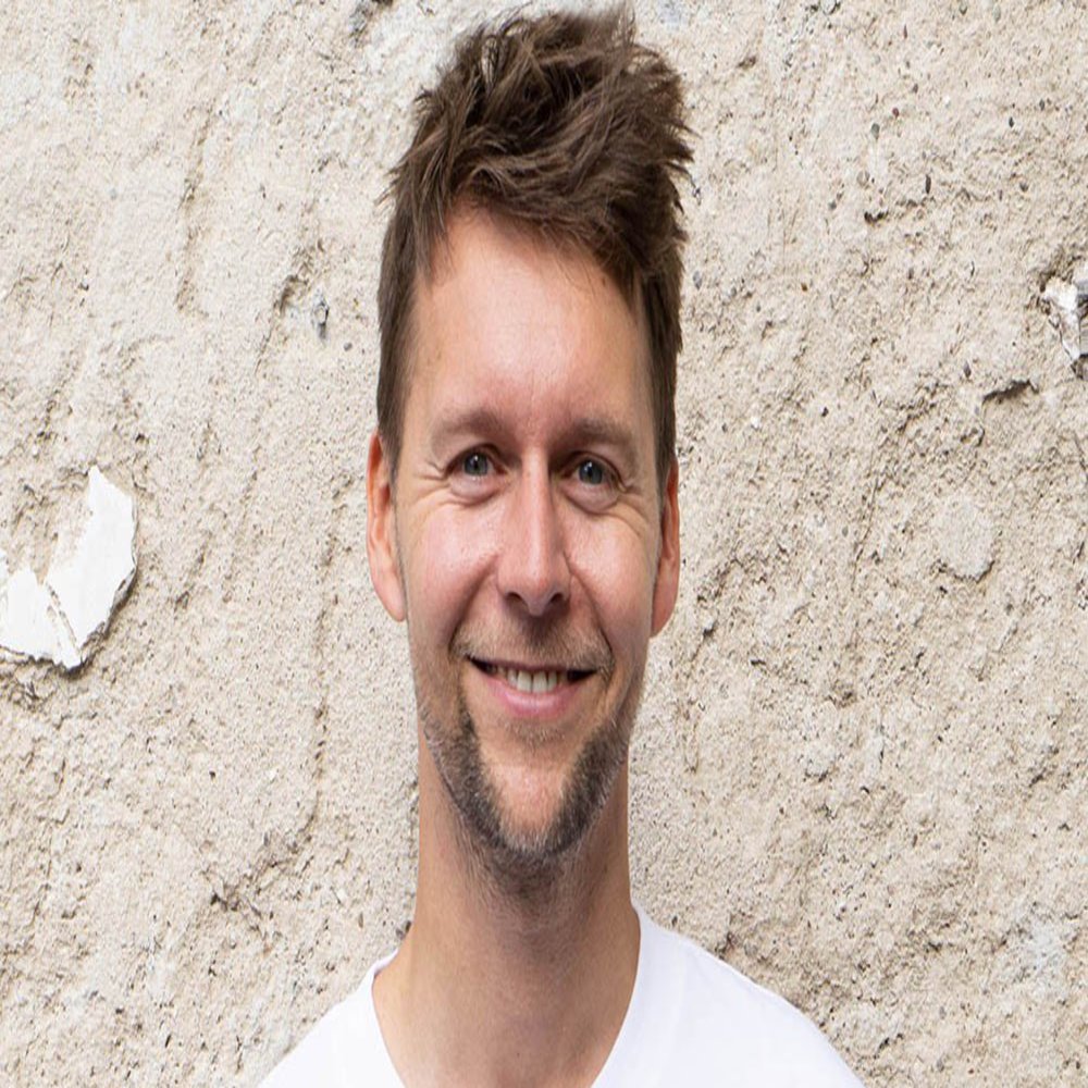 A man standing in front of a wall smiles at the camera