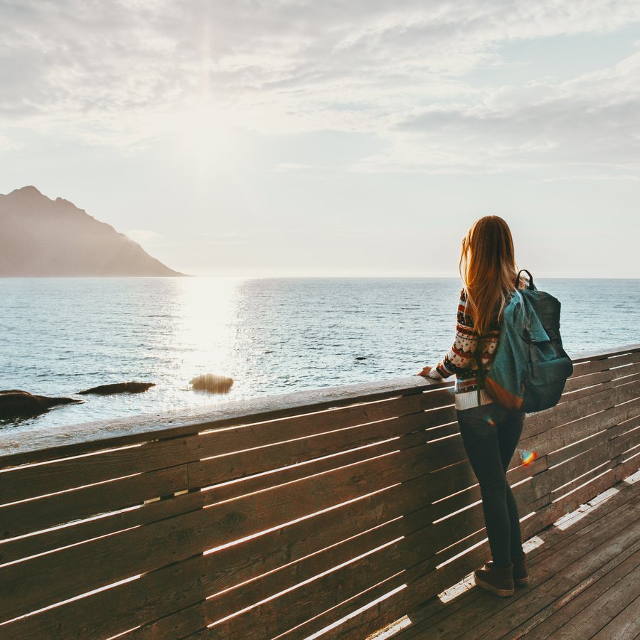 Traveler woman contemplating standing alone on bridge travel lif eine Frau steht an einer Brüstung am Wasser und blickt in die vor ihr liegende Weite