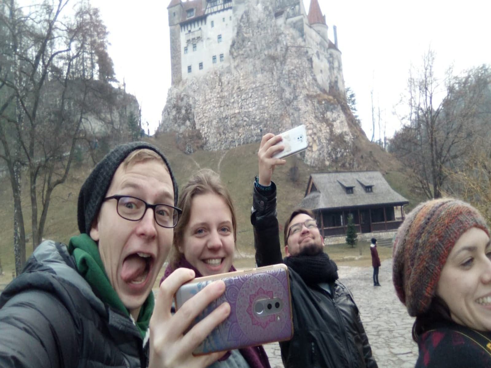 Eine Gruppe Studierender albert rum und schiesst Selfies. Im Hintergrund ist eine alte Steinburg zu sehen.