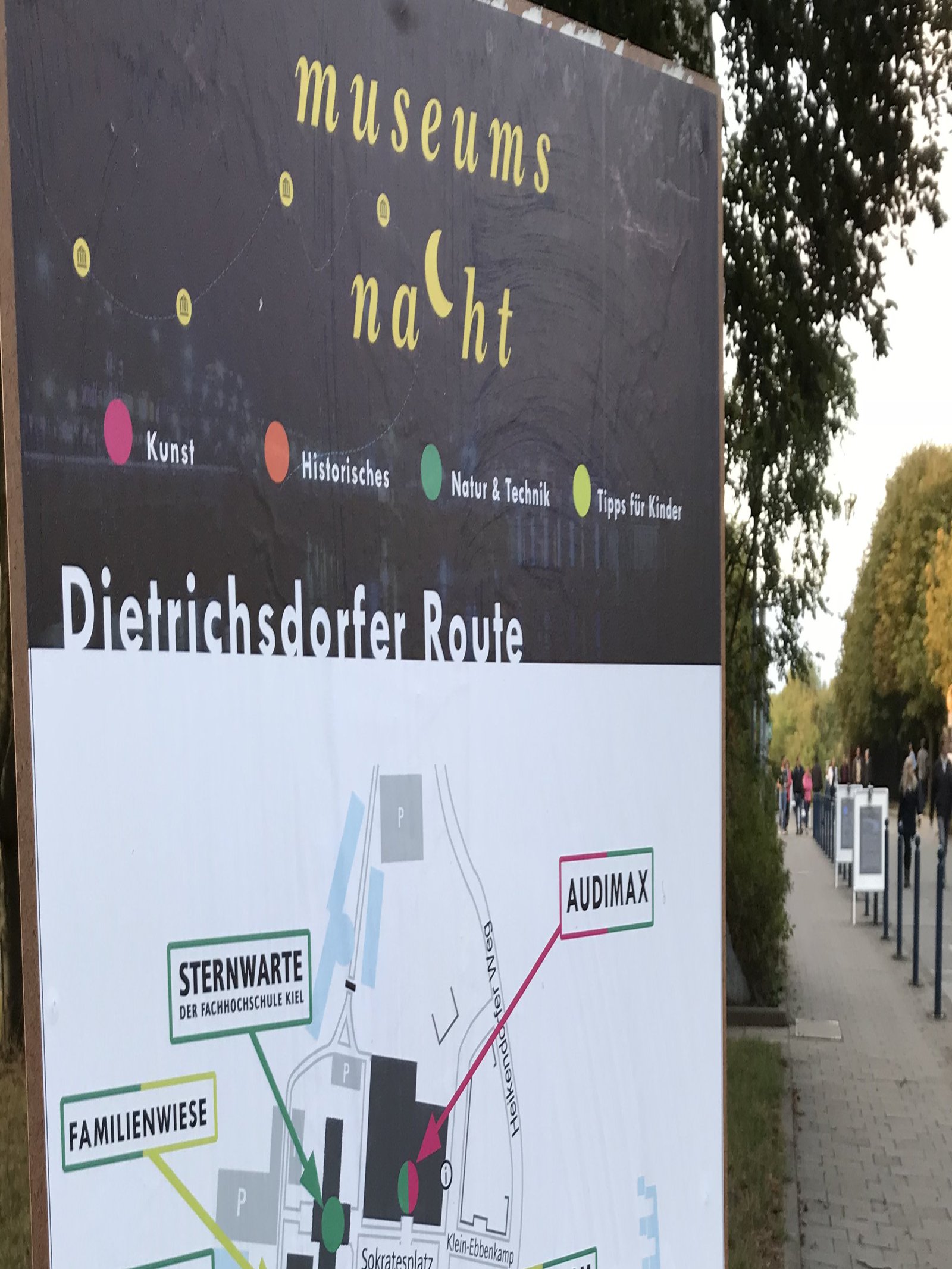 Ein im Freien hängendes Plakat zeigt den Gebäudeplan einer Hochschule.