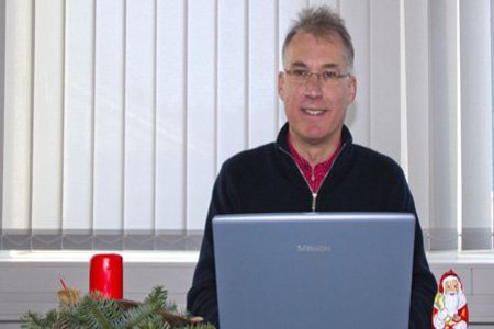 Ein Mann sitzt zufrieden vor seinem Laptop.