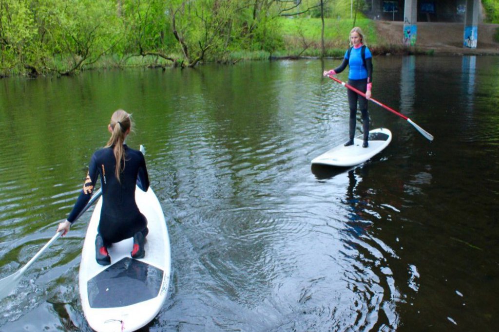 Zwei in Neoprenanzüge gehüllte Frauen auf ihren SUP-Boards.