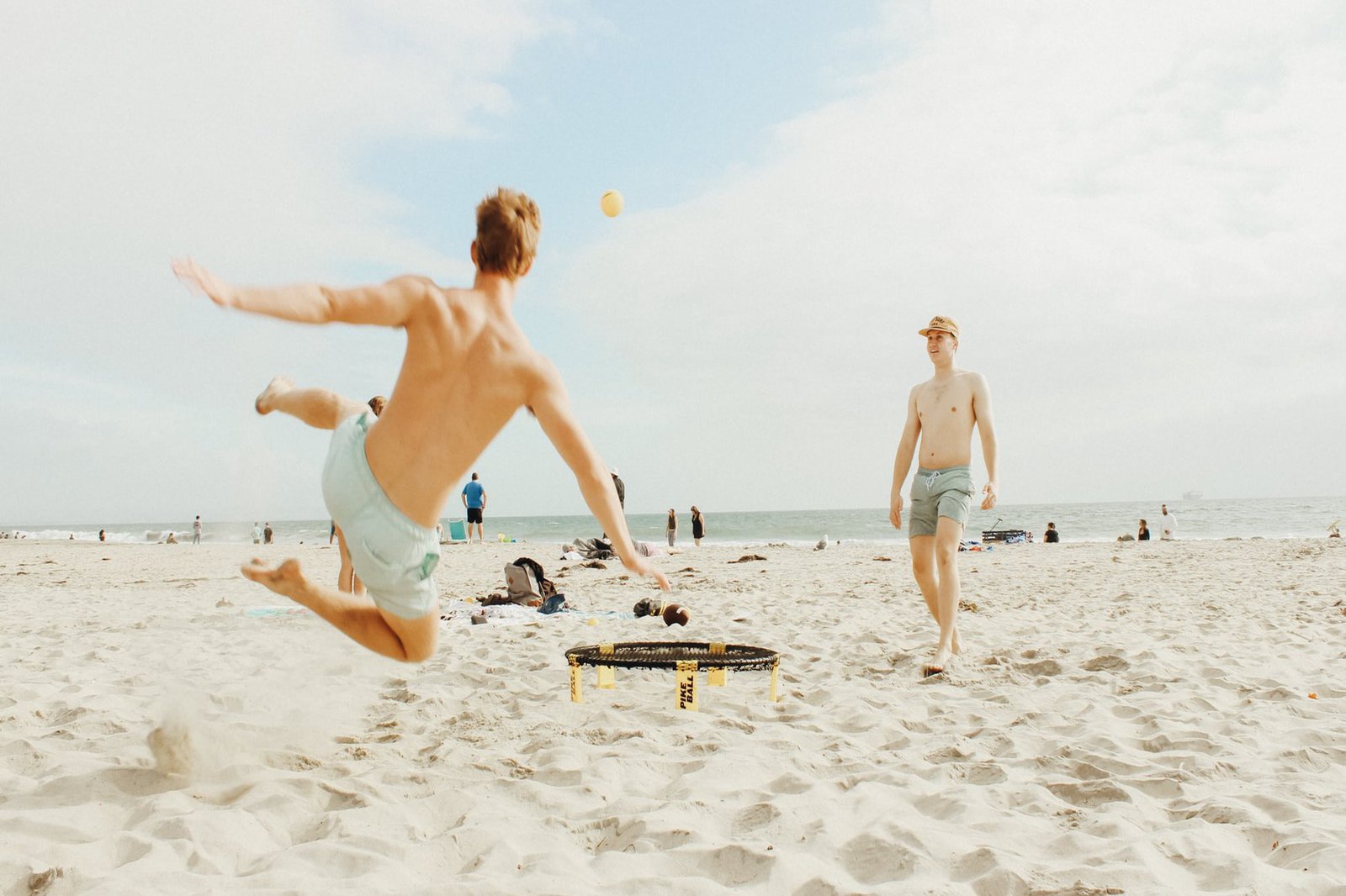Zwei Männer spielen Ball am Strand.