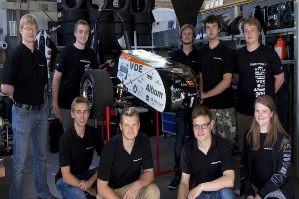 Ein Racing eam posiert stolz neben ihrem Rennwagen.