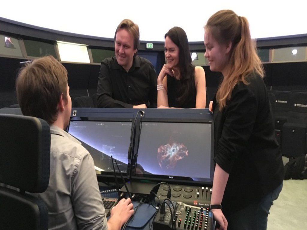 Zwei Frauen und zwei Männer stehen um das Steuerpult eines Vorführraums herum.