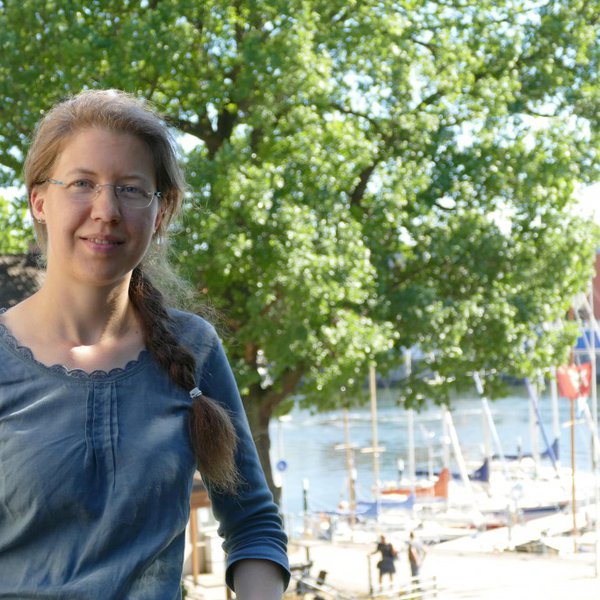 Eine Frau posiert auf einer Anhöhe, im Hintergrund ist unten ein Yachthafen zu sehen.