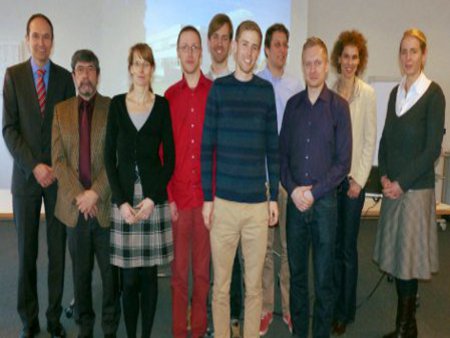 Die Projektgruppe versammelt sich vor der Leinwand, in einem Konferenzraum.