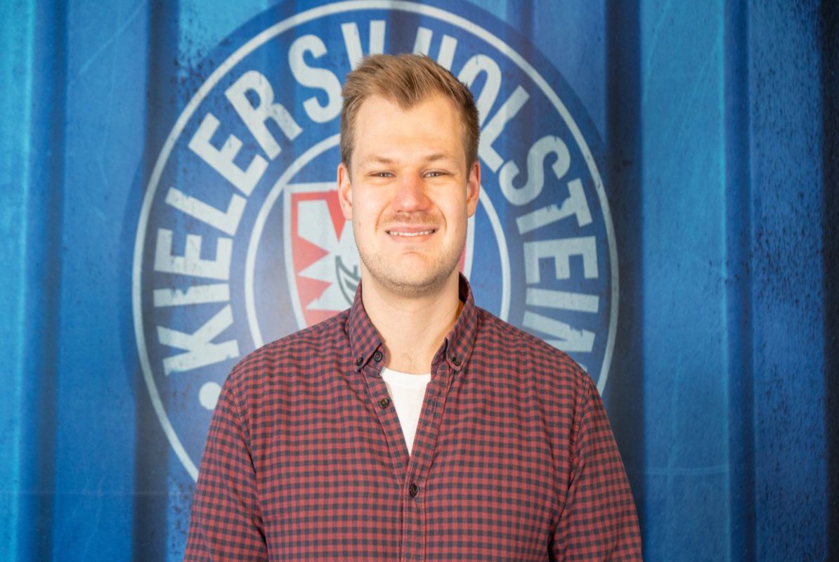 ein Mann im Hemd posiert für dem Logo des KSV Holstein Kiel