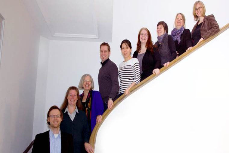 Das zu einem Großteil aus Frauen bestehende Team von MeQs, posiert auf einer Treppe.