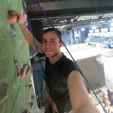 Frederik an einer Kletterwand, er grinst