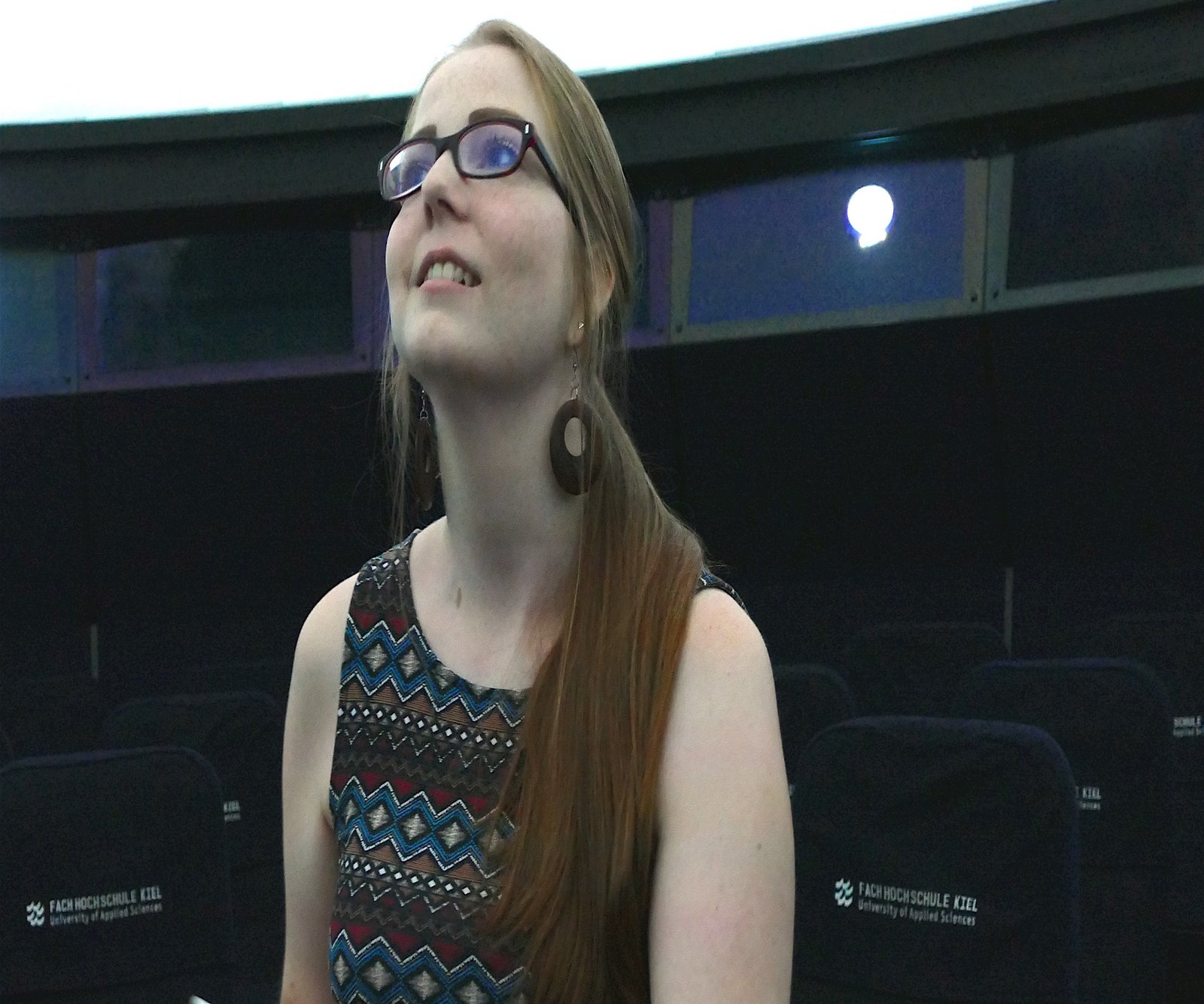 Eine mit Tablet und Pencil ausgestattete Frau schaut nach oben.