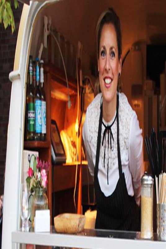 Eine Frau streckt feundlich ihren Kopf aus einem Kaffewagen. In der Auslage sieht man frisches Gebäck.