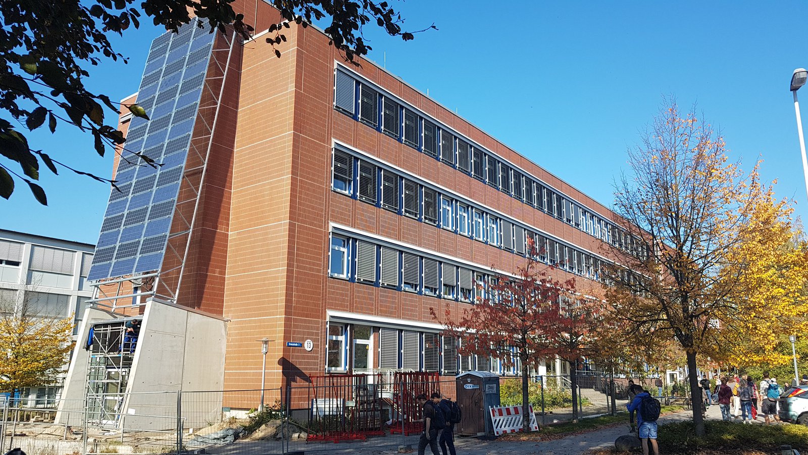 Ein Universitätsgebäude an dem mehrer Solarplatten angebracht sind.