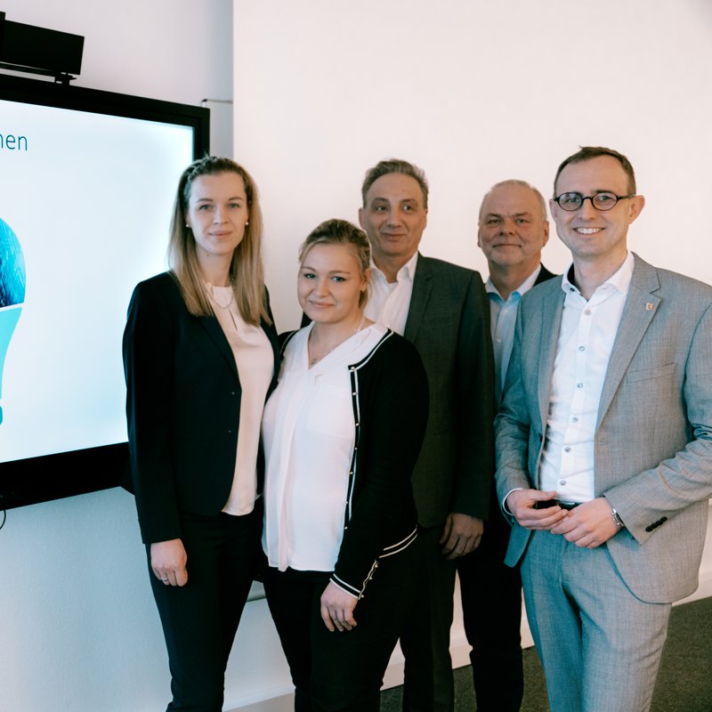Eine Gruppe von Menschen steht rechts von einem Bildschirm. v.l.n.r.: Irina Loza, Iwana Schmidt, Stephan Schneider, Karsten Böhmke und Dirk Schrödter