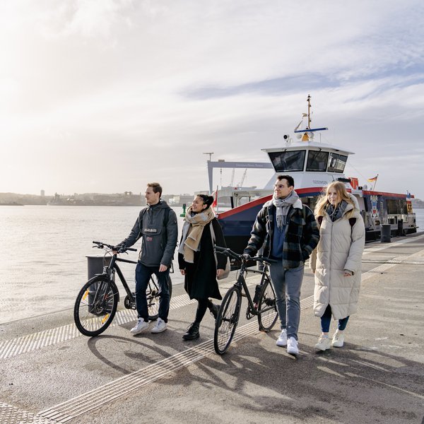 Studierende mit Fähre im Hintergrund