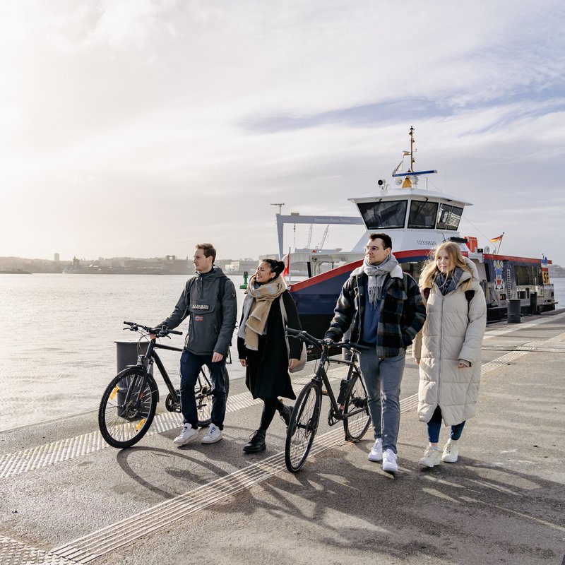 Studierende mit Fähre im Hintergrund