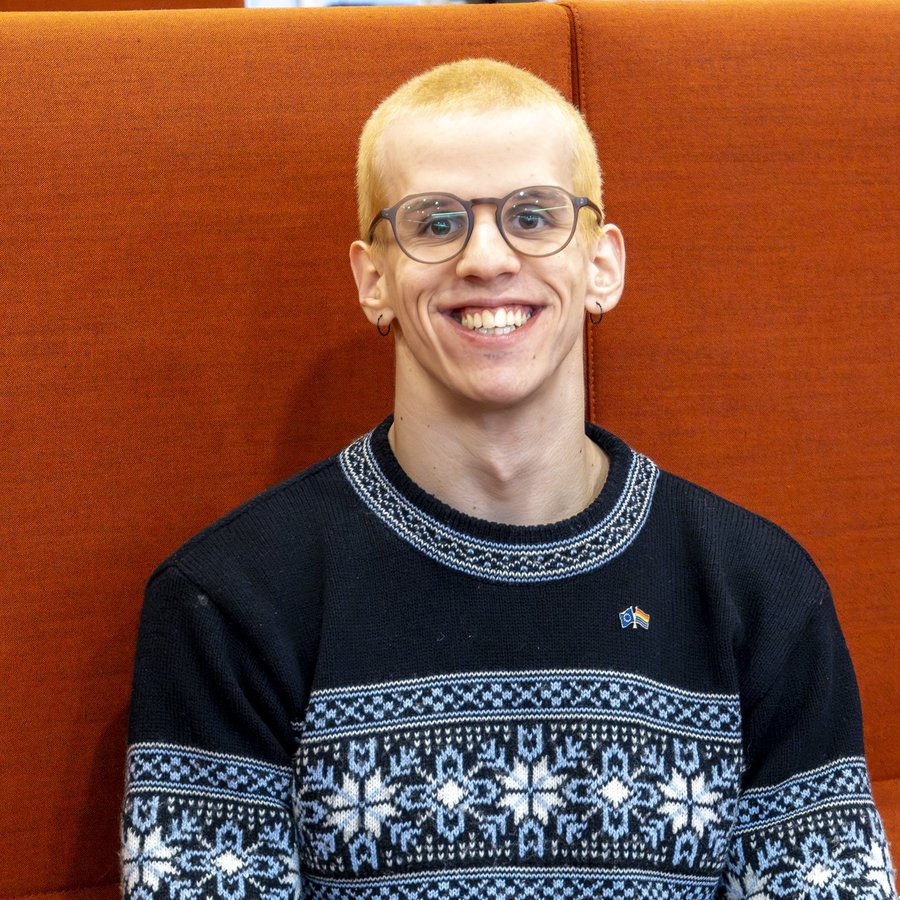 ein junger Mann mit kurzen roten Haaren lächelt in die Kamera