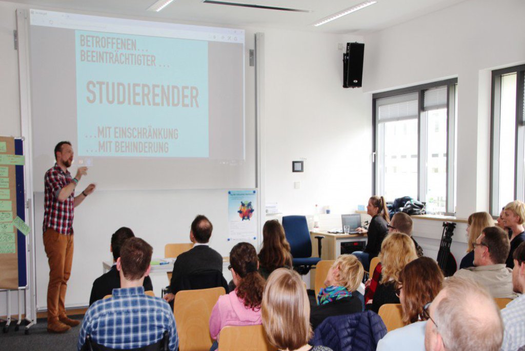 Ein Mann hält einen Vortrag vor einem interessierten Publikum.