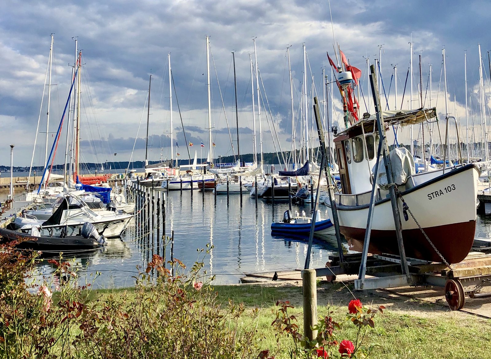 Das Bild zeigt einen Segelbootshafen, mit einem im Vordergrund aufgebockten Boot.