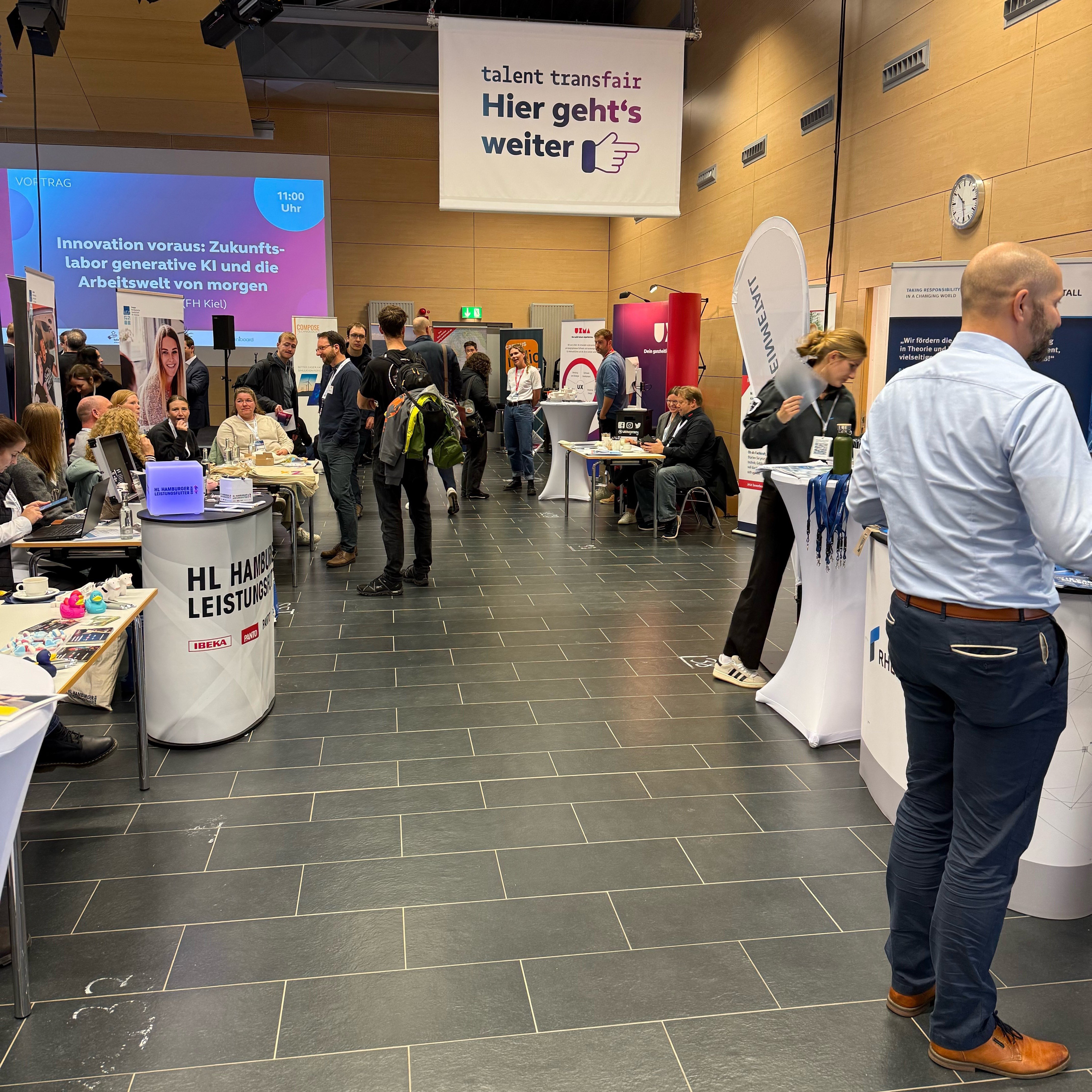 Blick in einen großen Raum, in dem Messestände aufgebaut sind.