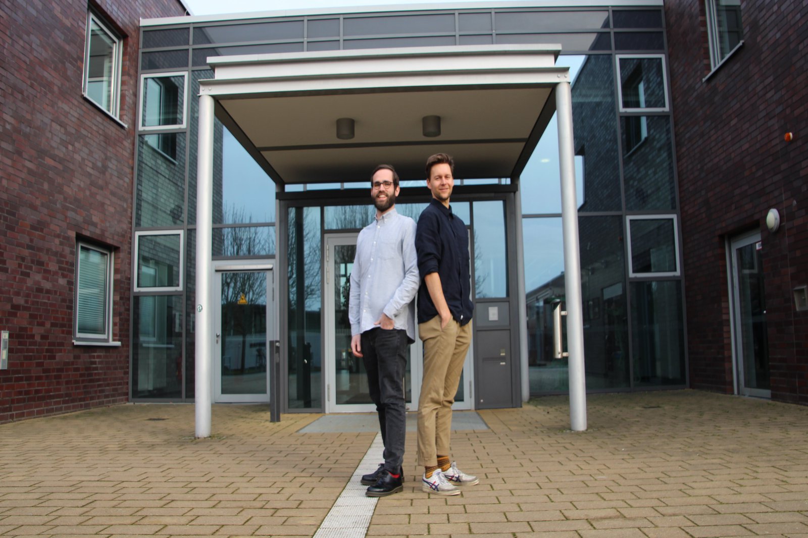 Zwei Männer stehen vor dem Haupteingang der FH Kiel.