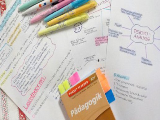 Bunte Stifte liegen auf Notzen zum Thema Pädagogik.