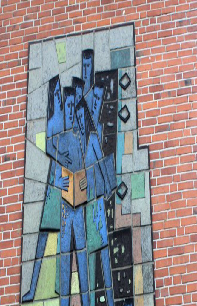 Ein großes blaues Mosaik, an einer Backsteinwand.