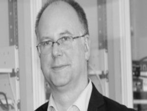 Das Schwarz-Weiß-Bild zeigt einen Mann in schwarzem Jackett.