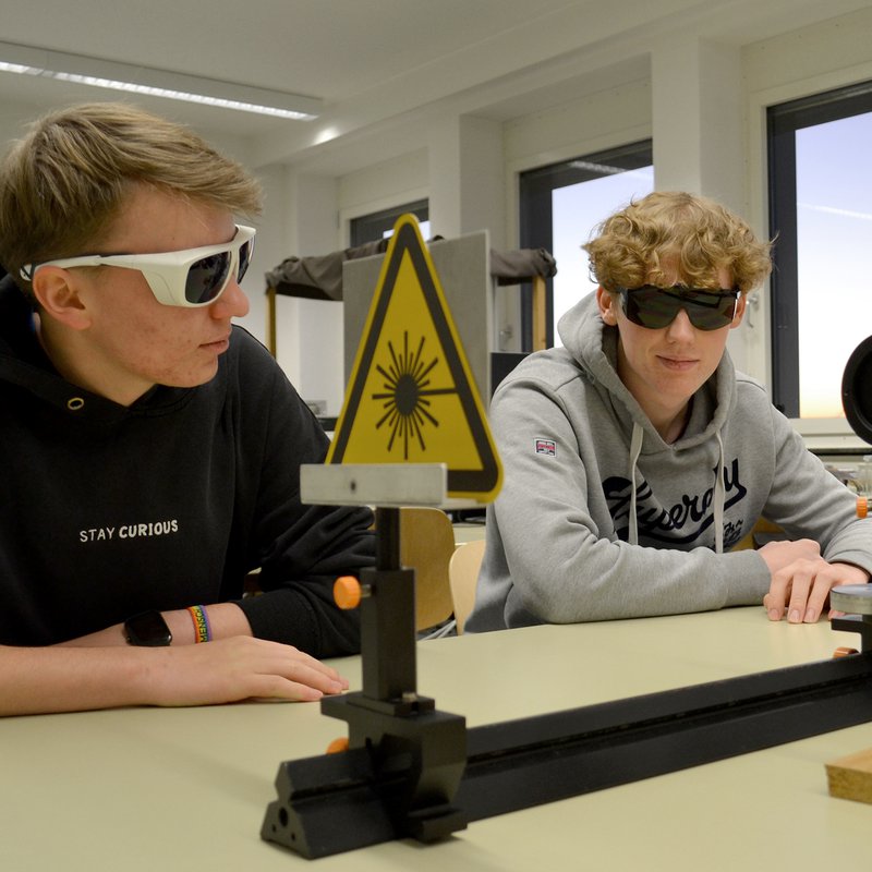 zwei Jungs mit Brillen sitzen vor einem technischen Gerät.